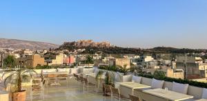 um pátio no último piso com mesas e cadeiras e uma cidade em Apollo Palm Hotel em Atenas