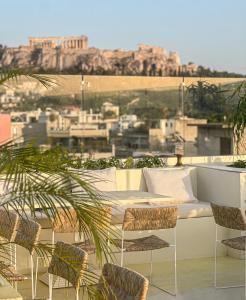 a balcony with a couch and chairs and a city at Apollo Palm Hotel in Athens