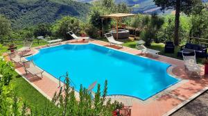 a large blue swimming pool with chairs around it at Fattoria La Palazzina in Radicofani