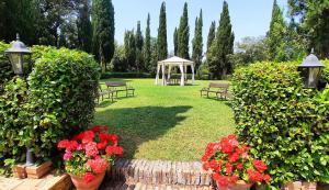 un giardino con panchine, gazebo e fiori di Fattoria La Palazzina a Radicofani