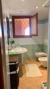 a bathroom with a sink and a toilet and a window at Casa Sofia vista porto in Olbia