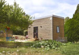 Cabaña de madera pequeña con mesa y sillas en La tiny house de la Blandinière, en Vertou