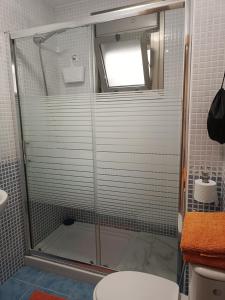 y baño con ducha y puerta de cristal. en APARTMENT ORANGE FUERTEVENTURA, en Puerto del Rosario