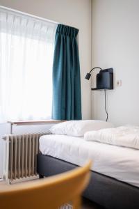 two beds in a hotel room with a window at The Tower Sportshostel in Sittard