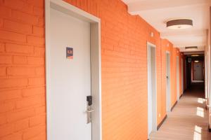 une porte ouverte dans un couloir avec un mur en brique orange dans l'établissement The Tower Sportshostel, à Sittard