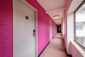 um corredor de um hospital com paredes cor-de-rosa em The Tower Sportshostel em Sittard