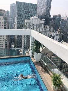 una mujer tendida en una piscina en la parte superior de un edificio en Park View KLCC ,by DeLive Home en Kuala Lumpur