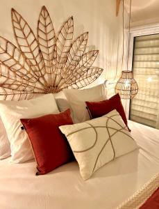 a white bed with red and white pillows on it at Bungalow Sucrier, les pieds dans l'eau in Terre-de-Haut