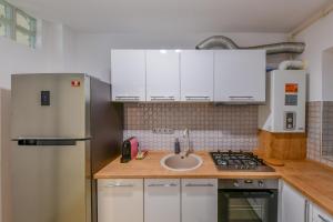La cuisine est équipée de placards blancs et d'un réfrigérateur blanc. dans l'établissement My Place Dorobantilor, à Cluj-Napoca