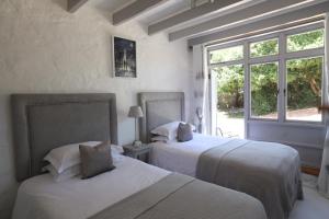 two beds in a white room with a window at Chapmans Peak Lodge Noordhoek Cape Town. in Cape Town +29 photos