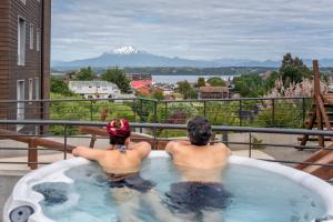 2 personnes assises dans un bain à remous donnant sur une montagne dans l'établissement Exquisito Depto con Vista al Lago y Tinaja, à Puerto Varas