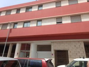a red building with cars parked in front of it at APARTMENT ORANGE FUERTEVENTURA in Puerto del Rosario