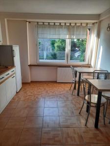 a kitchen with tables and chairs and a large window at Emides in Pobierowo
