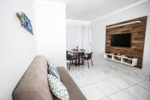 Sala de estar con sofá, TV y mesa en Apto Taperapuan 2 quartos com piscina perto praia, en Porto Seguro