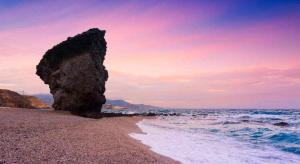 uma grande rocha sentada numa praia junto ao oceano em LAS PITAS Piso a metros de la playa em Carboneras