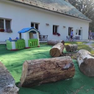 einen Hof mit einem Spielplatz mit Holzscheiten und einem Haus in der Unterkunft Penzion Smrekovica in Ružomberok