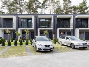 dois carros estacionados num parque de estacionamento em frente a um edifício em Terraced houses, outdoor pool, Pobierowo em Pobierowo