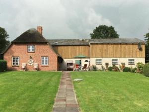 a large red brick house with a grass yard at Holiday home in Westerhever with a fireplace and a beautiful garden in Westerhever