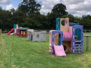 a group of playground equipment in a grass field at The Dairy-Petting Farm-Indoor Pool-Play Areas-Parkland-Woodland-Lake,Ponds&Stream-min2 night stay in Lechlade