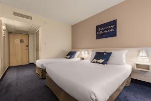 um quarto de hotel com duas camas e uma placa na parede em Ace Hôtel Clermont Ferrand La Pardieu em Clermont-Ferrand