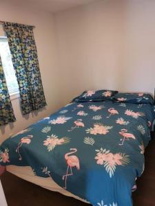 a bed with a blue comforter with pink flamingos on it at Pigeon Lake Cottage in Kawartha Lakes