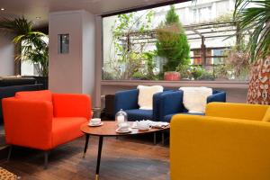 ヴァンドームにあるLogis Hôtels Le Saint Georgesのカラフルな椅子とコーヒーテーブルが備わる客室です。