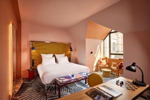 a bedroom with a bed and a desk and a table at Mama Shelter Dijon in Dijon