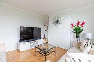 sala de estar blanca con TV y mesa en Cosy 3 Bed Flat Ideal for Trips to London en Londres