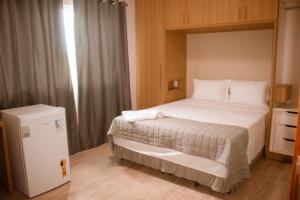 a bedroom with a large bed and a small refrigerator at Maper Ouro in Parauapebas