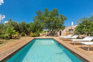 ein Außenpool mit Holzdeck und Liegestühlen in der Unterkunft Trullo Kalia by BarbarHouse in San Michele Salentino