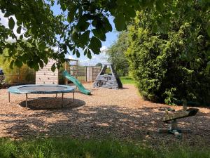 a playground with a trampoline and a swing set at The Parlour-Farm Stay-IndoorPool-Play Areas-Parkland-Woodland-Lake-Ponds-min 2 nights in Lechlade