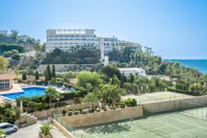 una pista de tenis frente a un complejo y el océano en Eurotennis Paradise Beach Apartments, en Villajoyosa