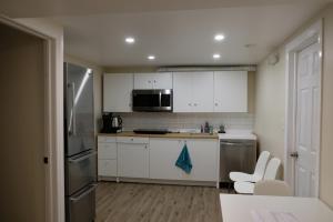 una cocina con armarios blancos y electrodomésticos de acero inoxidable en Katie en Charlottetown
