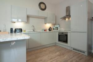 a kitchen with white cabinets and a clock on the wall at School House in Malmesbury