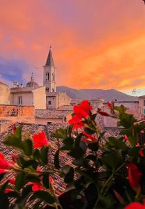 a building with a clock tower and red flowers at Regina d’Aragona casa vacanze in Sulmona
