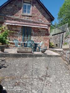 un patio con sillas y una mesa frente a una casa en Gîte à Noailhac ferme au calme bourg & église XII en Noailhac