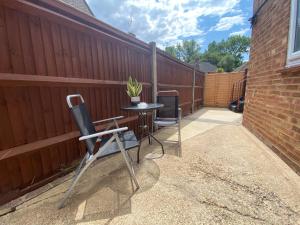 eine Terrasse mit einem Tisch und Stühlen neben einem Zaun in der Unterkunft Cristina Modern in Horley