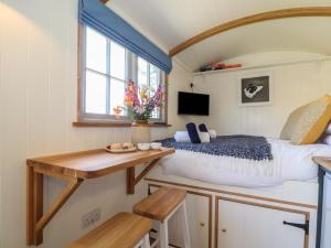 1 dormitorio con cama, escritorio y ventana en Bosulla Shepherds Hut en Penzance