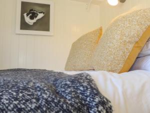 een bed met kussens en een foto aan de muur bij Bosulla Shepherds Hut in Penzance