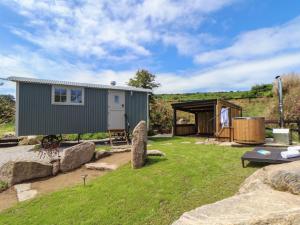 a green tiny house in a yard with rocks at Bosulla Shepherds Hut in Penzance