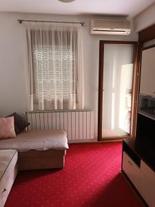 a bedroom with a bed and a window and red carpet at New Point in Zagreb