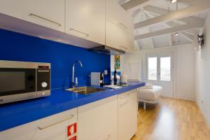 a kitchen with white cabinets and a blue wall at Downtown Cosy Suite VI in Porto