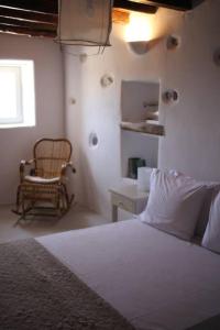 a white bedroom with a bed and a chair at A casa d’ Irene in Kampos Paros