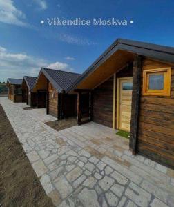 a row of wooden houses with a stone walkway at Vikendice Moskva Uvac in Sjenica