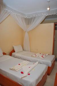 two beds in a room with roses on them at Caphill Hotel in Syokimau