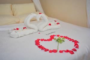 Una cama con toallas y un corazón hecho de rosas. en Caphill Hotel en Syokimau