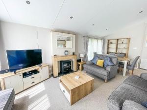 a living room with a television and a couch and a table at Beautiful Lodge With Decking At Breydon Water Park In Norfolk Ref 10022b in Belton