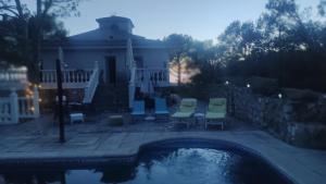 un patio trasero con una piscina con sillas y una casa en Increíble Casa Rural en la Sierra de Altomira, en Albalate de Zorita