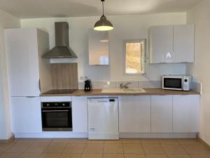 a kitchen with white cabinets and a sink and a microwave at APPARTEMENT TERRASSE La Citadelle Appartements Saint Florent in Saint-Florent