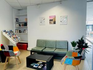 ein Wohnzimmer mit einem grünen Sofa und Stühlen in der Unterkunft Auberge de Jeunesse HI Rennes in Rennes